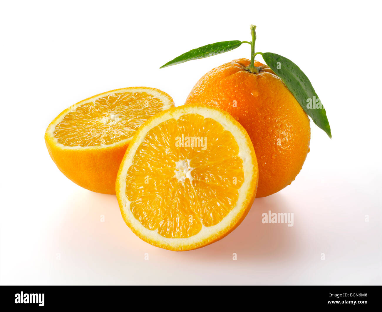 Frische Orangen ganze und geschnittene Hälften mit Blättern Stockfoto