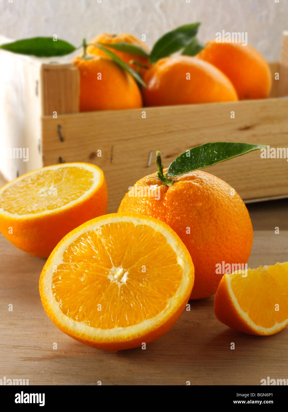 Frische Orangen ganze und geschnittene Hälften mit Blättern in einer Schachtel Stockfoto