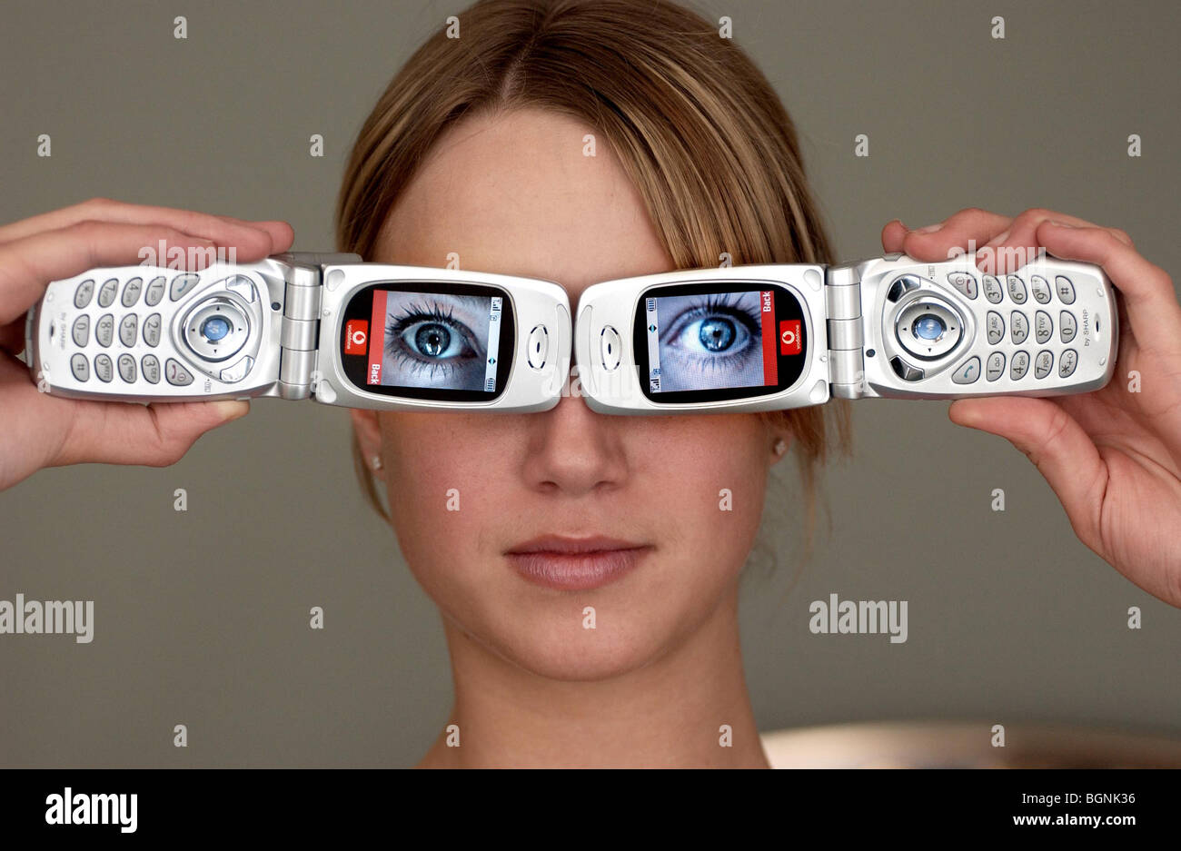 Ein Mädchen mit zwei mobilen Kamera-Handys mit Bildern der großen Augen Stockfoto