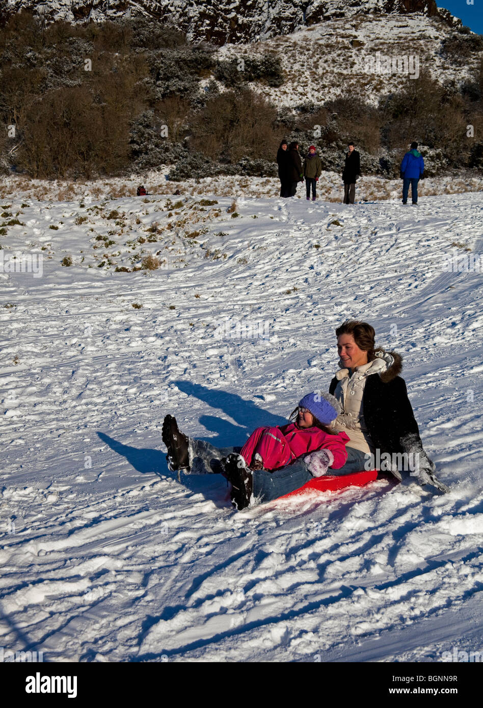 Mutter und Tochter Spaß Schlittenfahren im Schnee Holyrood Park, Edinburgh, Schottland, UK Europe Stockfoto