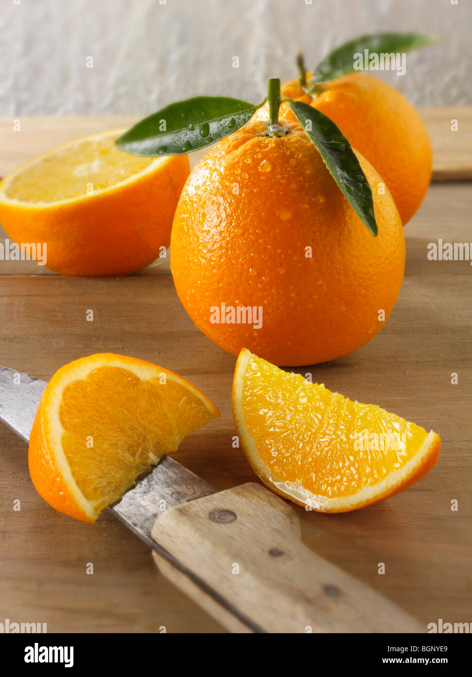 Ganze und geschnittene frische Orangen mit Blättern in einer Küche Stockfoto