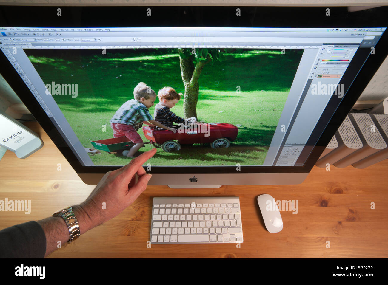 Apple iMac 27' Computer im home-Office Schreibtisch mit externen Festplatten, drahtlose Tastatur und Maus - hand zeigen Stockfoto