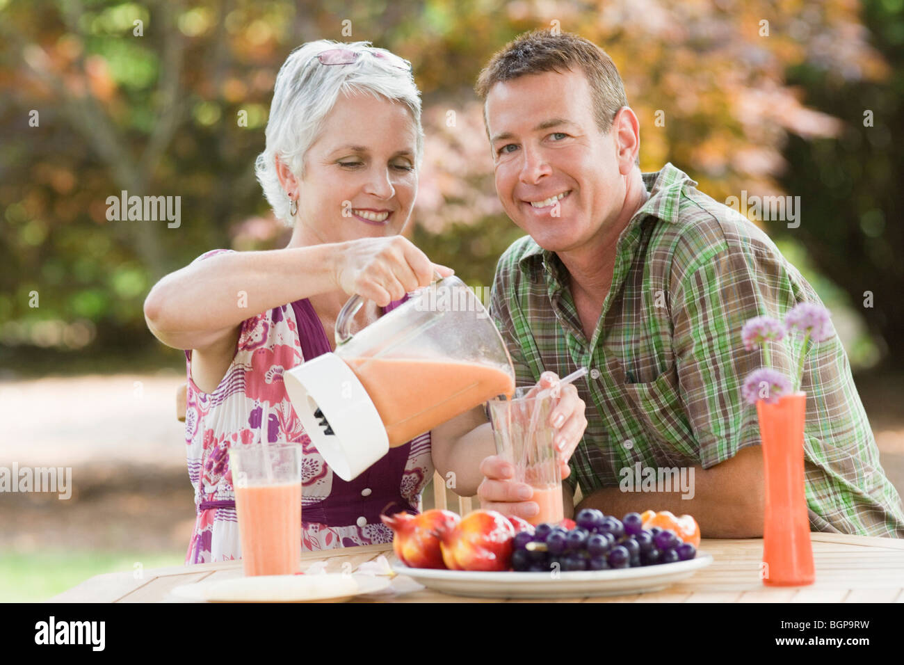 Reife Frau strömenden Saft in ein Glas mit einem reifen Mann neben ihr Lächeln Stockfoto