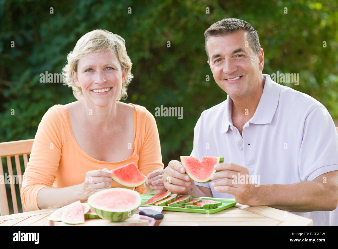 Porträt von ein älteres Paar an einem Tisch sitzen und halten Scheiben Wassermelone Stockfoto