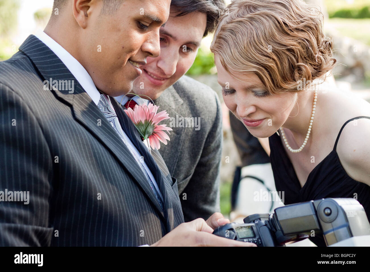 Gäste bei einer Hochzeit betrachten in der Vorschau einer digitalen Kamera ein Foto. Stockfoto