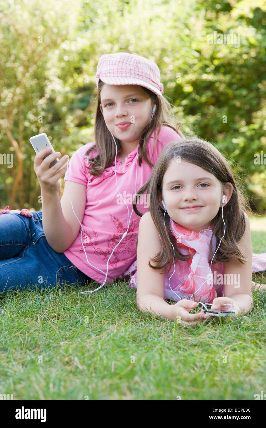 Porträt von zwei Schwestern anhören von MP3-Player in einem park Stockfoto