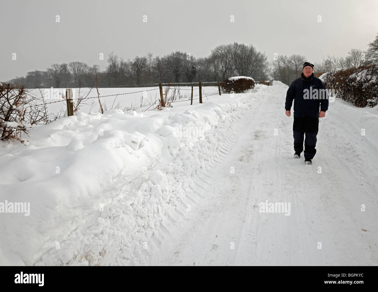 Mann, in einer verschneiten Straße entlanggeht. Stockfoto