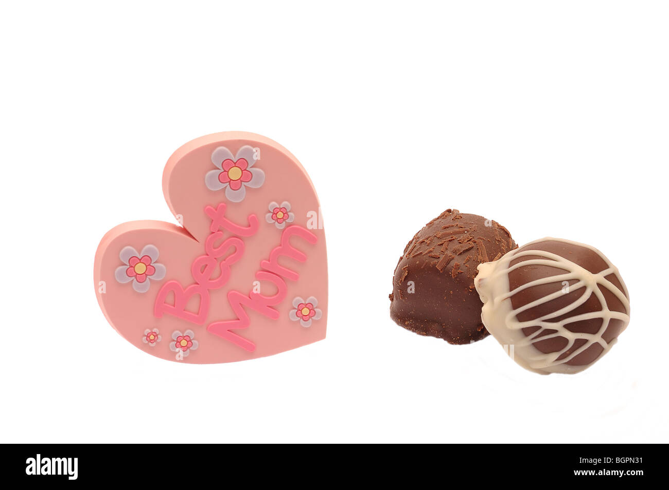 Herzförmige Mütter Tag Abzeichen zeigt beste Mama auf weißem Hintergrund mit zwei Pralinen, Ideal für Grußkarte Stockfoto