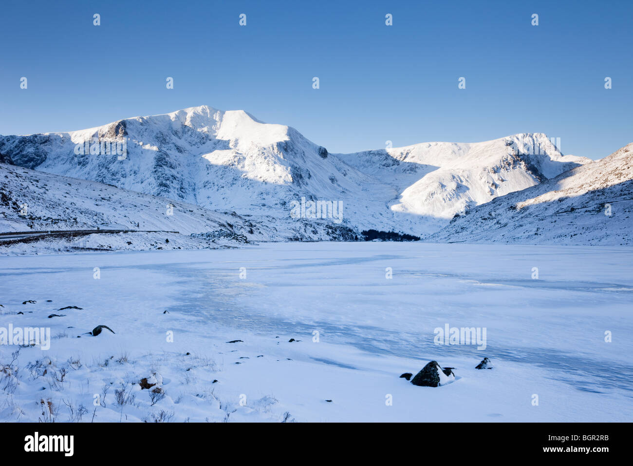 Ogwen Valley, North Wales, UK. Blick über den zugefrorenen Llyn Ogwen See, Y Garn mit Schnee bedeckten Bergen im winter Stockfoto