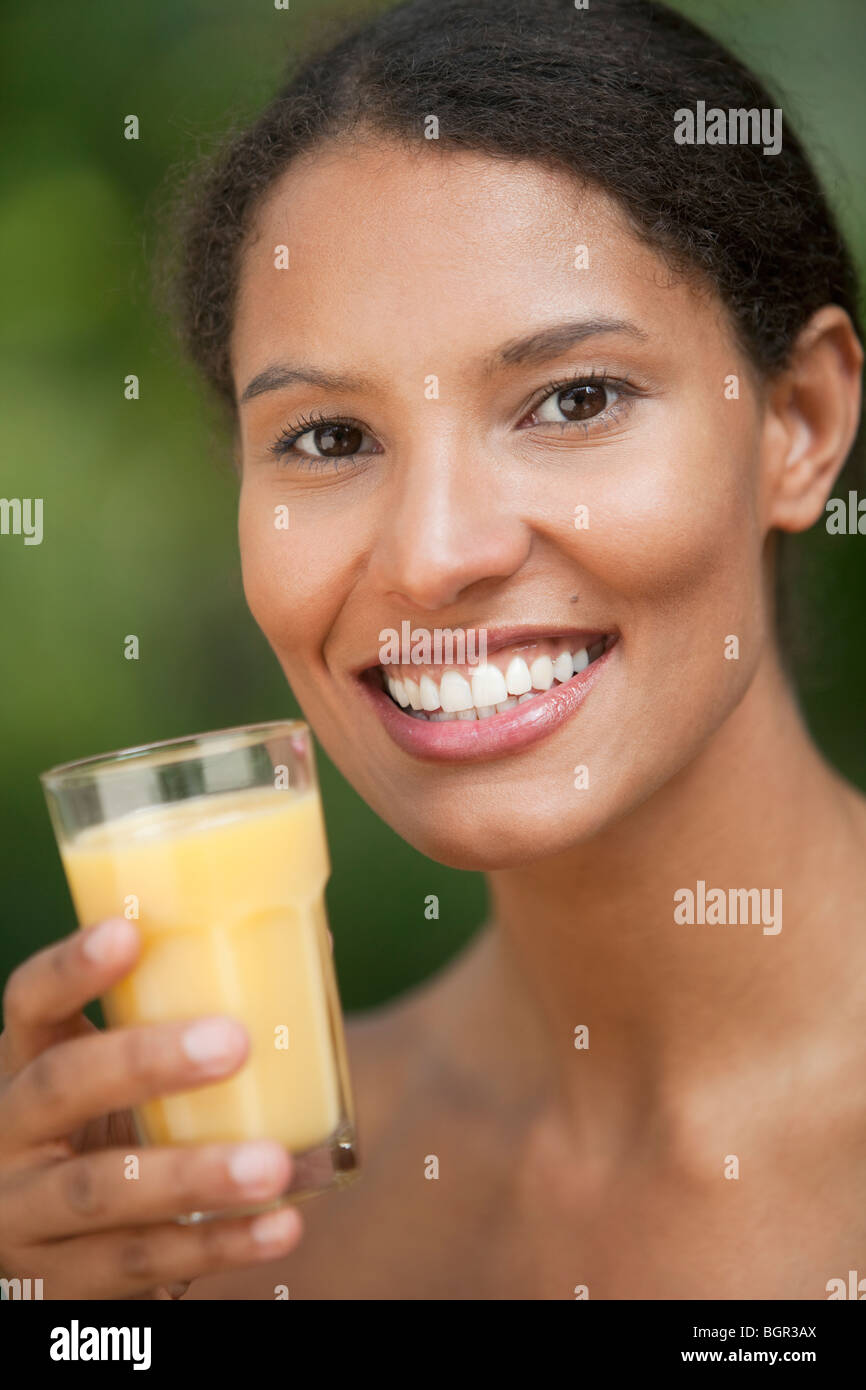 Nahaufnahme der jungen Frau trinkt Orangensaft im Freieneinstellung. Vertikal gerahmte Schuss. Stockfoto