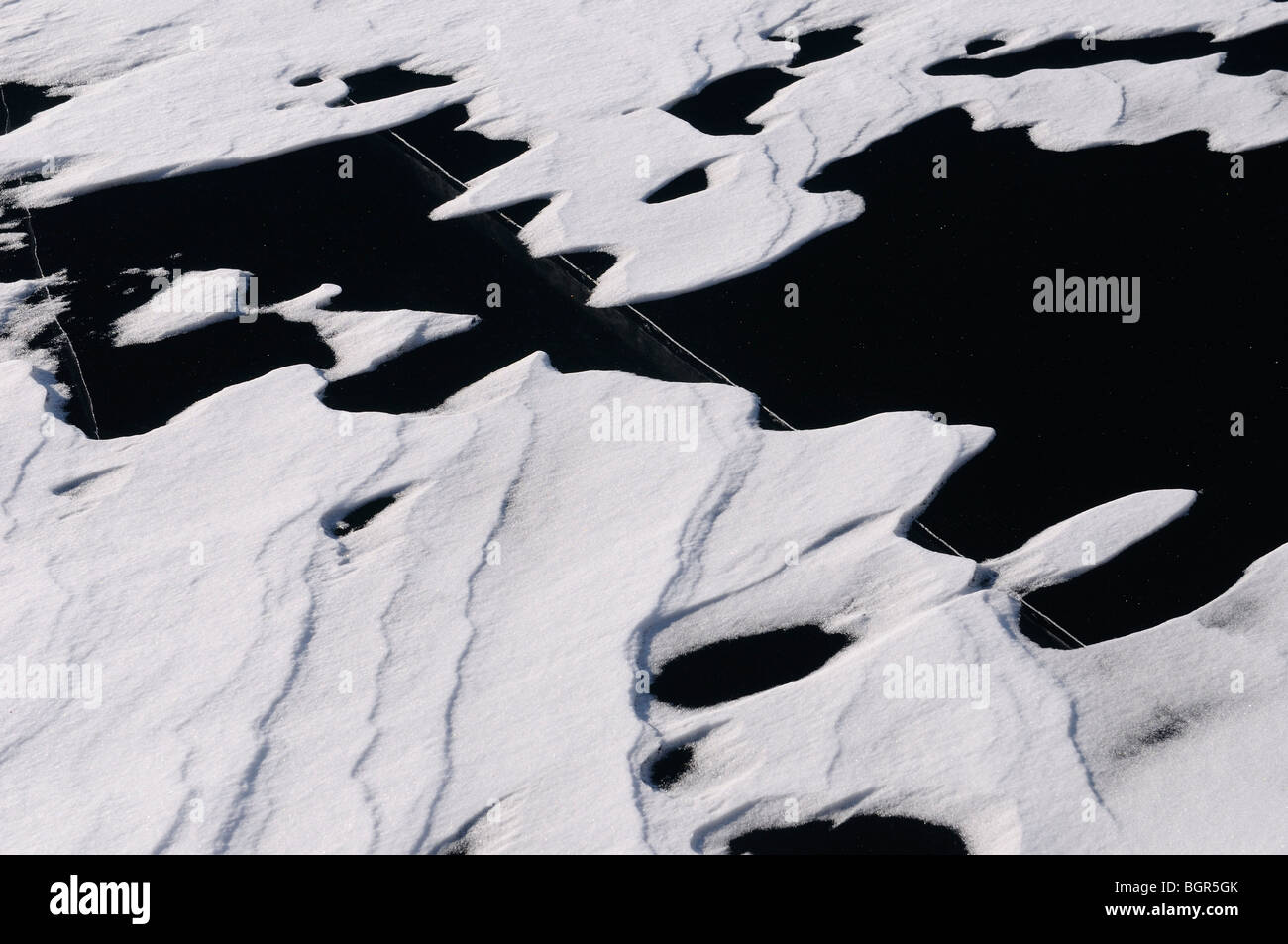 Snow Drift Muster auf dicken Glatteis auf einem See mit einer tiefe Risse Stockfoto