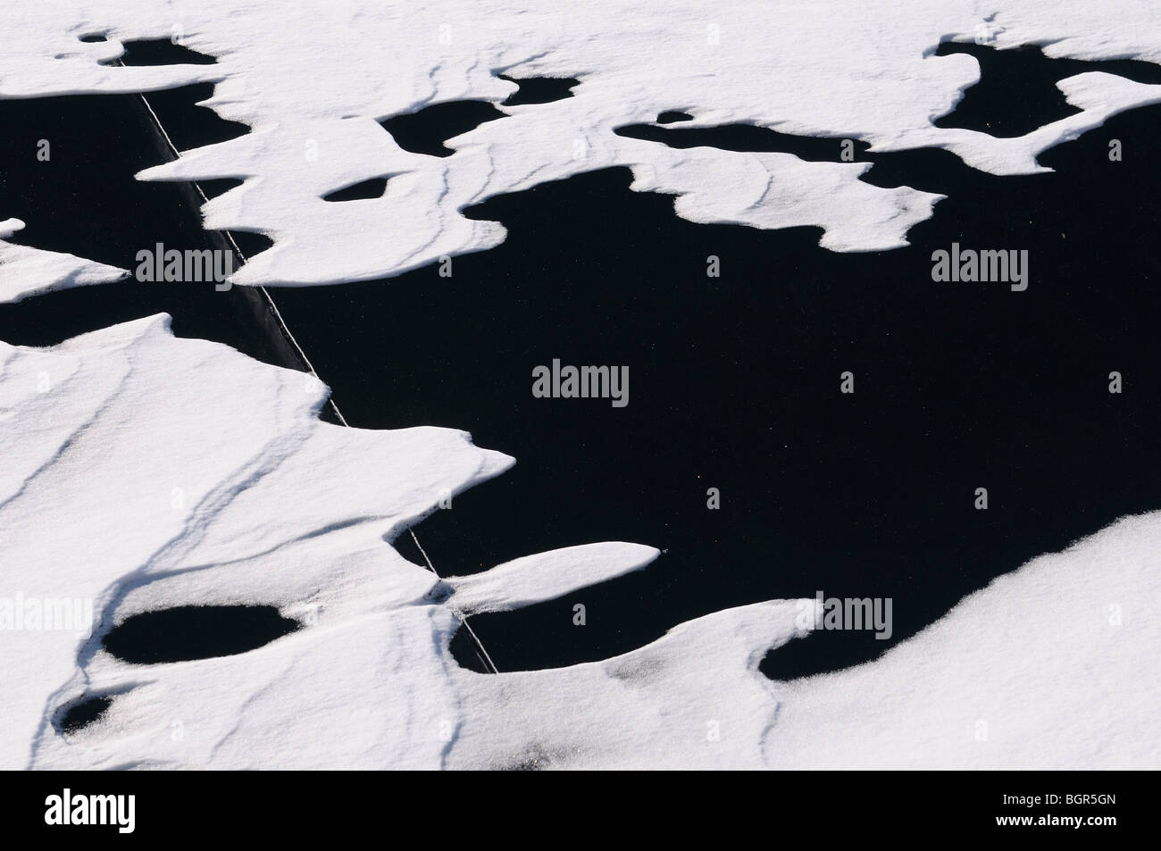 Snow Drift Muster auf Glatteis auf einem See mit einem großen tiefen Riss Stockfoto