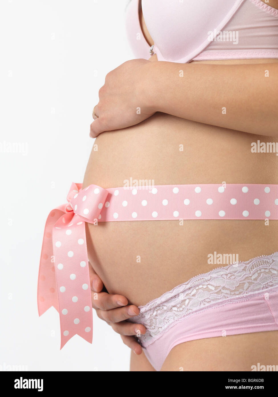 Schwangere Frau mit einer rosa Schleife am Bauch Stockfoto