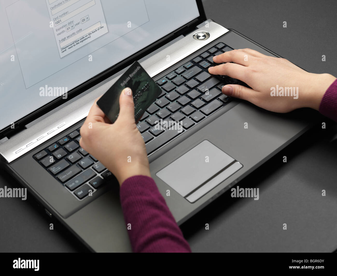 Frau an einem Laptop sitzen und ihre Kreditkarten-Informationen in ein Onlineformular eingeben Stockfoto