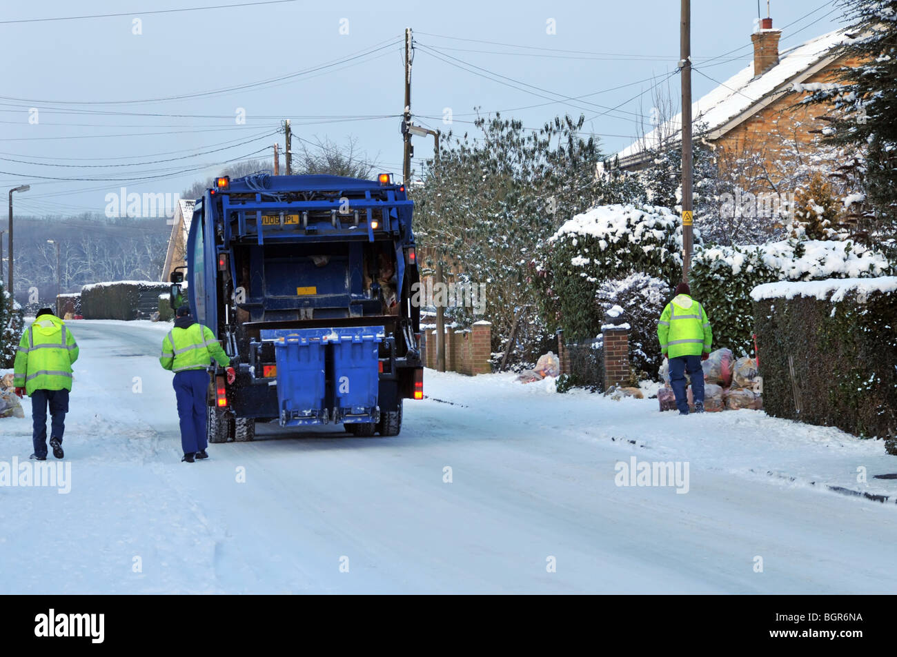 Müllwagen LKW und Binmen auf eisigen Schnee bedeckt Wohnstraße Stockfoto