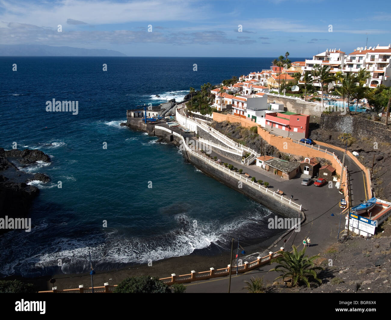 Kleine Strand Playa Puerto Santiago und Fischerhafen auf Teneriffa mit der Insel La Gomera am Horizont Stockfoto