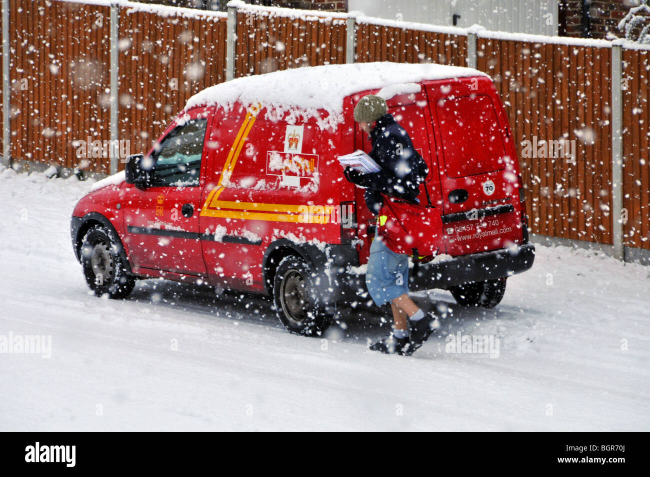 Kaltes Winterwetter schneit auf Royal Mail Lieferung Postmann arbeiten Aus Postauto in Wohnstraßenlandschaft im Schneesturm Brentwood Essex England Großbritannien Stockfoto