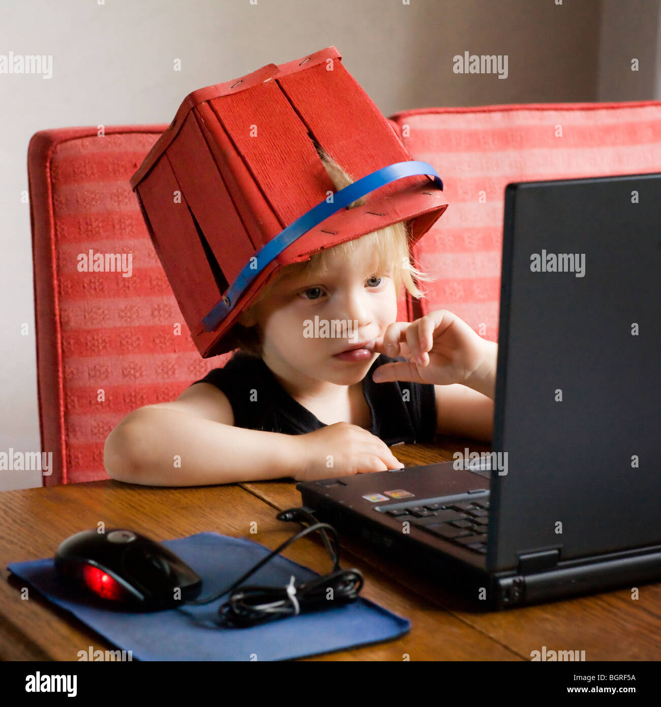 Junge mit einem Korb auf dem Kopf einen Film auf einem Laptop, Schweden. Stockfoto
