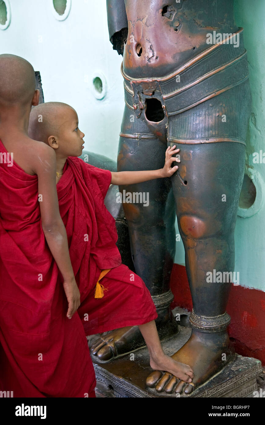 Junge buddhistische Mönche die Khmer Bronze Skulptur berühren. Mahamuni Paya. Mandalay. Myanmar Stockfoto
