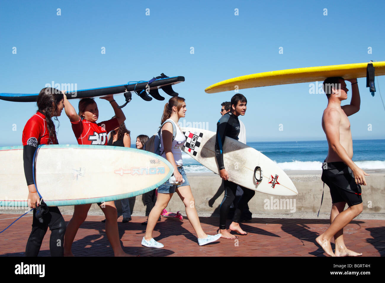 Spanische Jugendliche tragen Surfbretter zu Beginn der Surfkurs Stockfoto