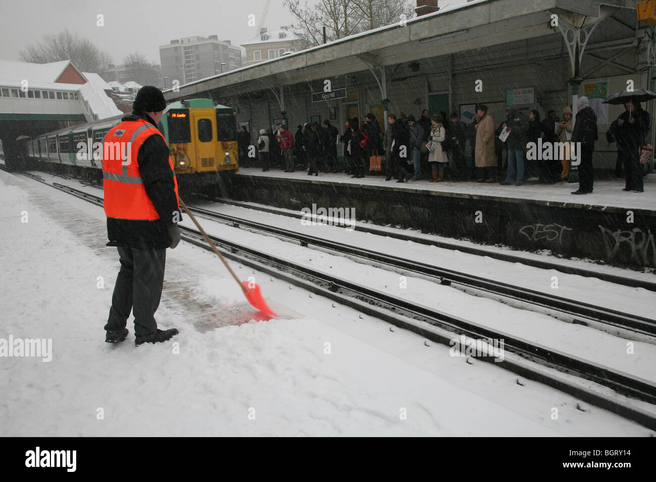 Pendler warten auf ihren Zug bei Schneefall auf einer Staion in Süd-London, UK Stockfoto