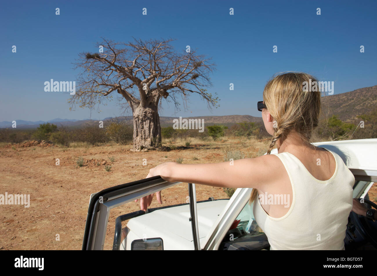 Junge Frau neben Kfz Blick auf Baobab-Baum, Epupa Wasserfälle Gebiet Kaokoland, Namibia Stockfoto