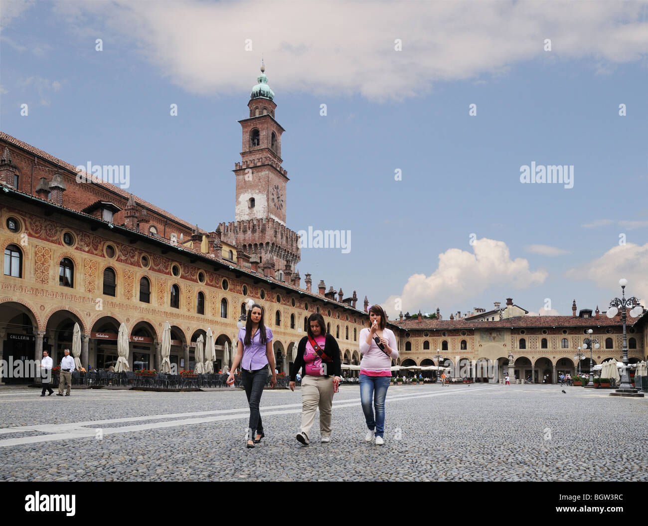 Junge Frauen mit Bramante Turm im Castello Sforzesco in Piazza Ducale Vigevano Lombardei Italien mit Arkaden oder portici Stockfoto