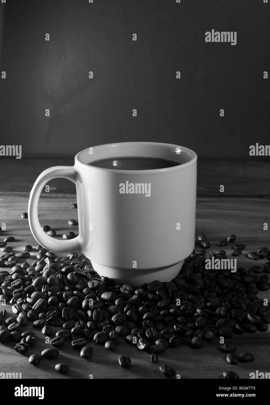 Weiße Tasse Kaffee sitzen in einem Haufen von frischen Kaffeebohnen auf schwarzem Hintergrund Stockfoto