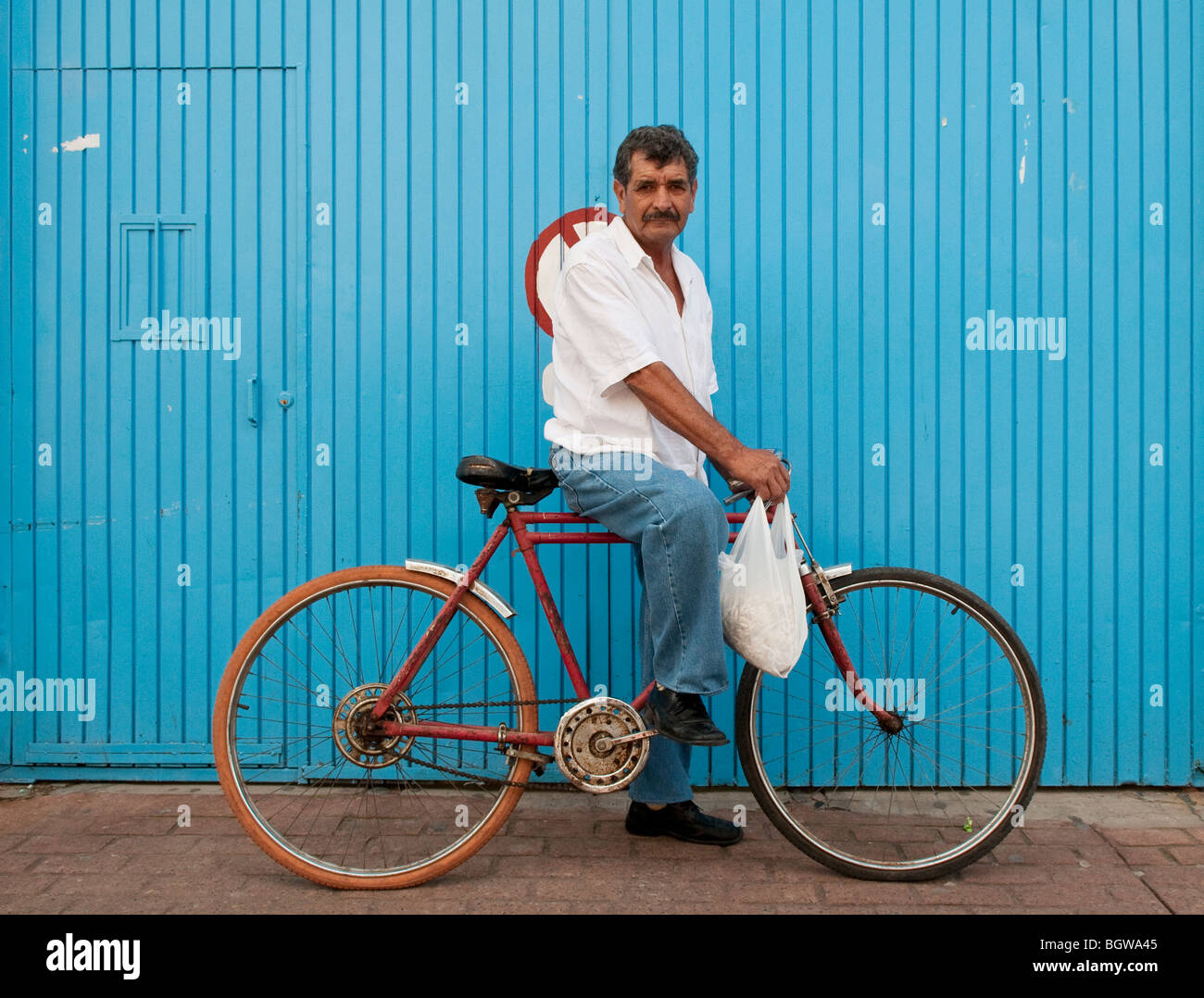 Mann auf dem Fahrrad vor blauer Wand, Tonalá, Mexiko. Stockfoto