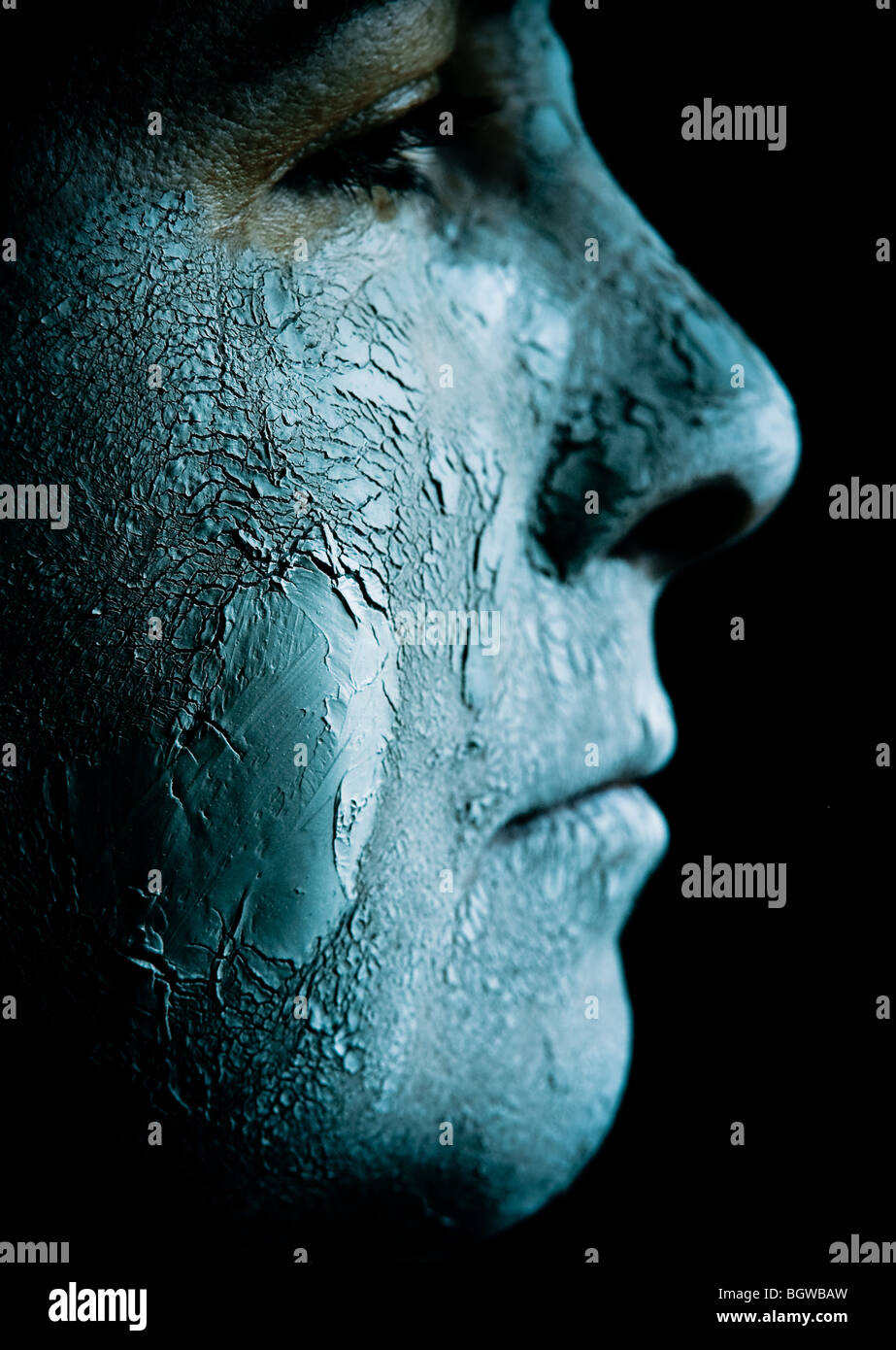 Ein Profil von einem mittleren gealterten Frau konfrontiert ist, festsitzende in ein ausgetrocknetes, Schlamm-Maske knacken. Stockfoto