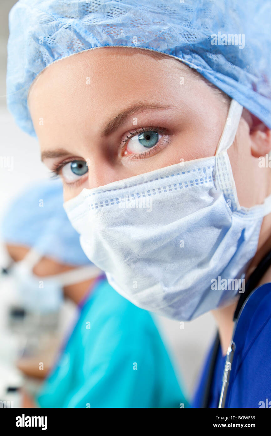 Eine blonde medizinische oder wissenschaftliche Forscherin oder Arzt tragen einen Mundschutz in einem Labor mit ihrem asiatischen Kollegen Stockfoto