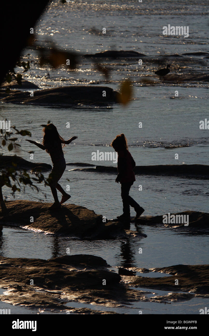 SILHOUETTE ZWEI KINDER SPAß SPRINGEN VON FELS ZU FELS SPIELEN IM FLUSS GEORGIEN KEIN MODELL FREIGEBEN Stockfoto