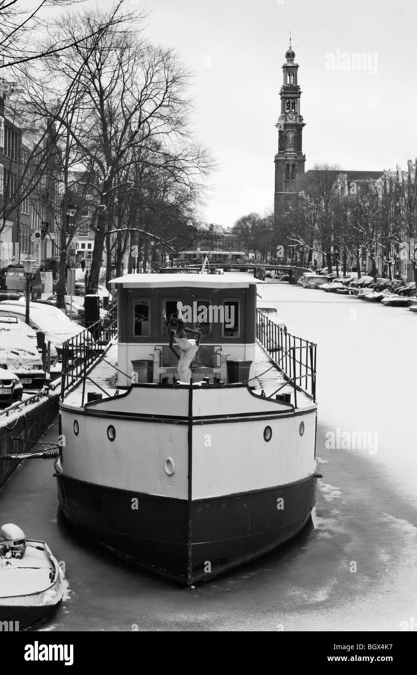 Hausboot auf gefrorenen Amsterdam Canal mit der Westertoren (Western Kirchturm) im Hintergrund Stockfoto