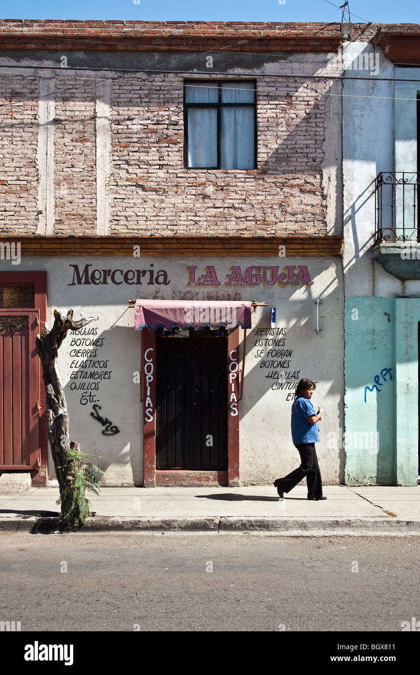 einsame Frau Fußgänger Pässe kleine Trockengüter Laden geschlossen für die Siesta am Nachmittag an einem feinen sonnigen Nachmittag in Oaxaca-Stadt Mexiko Stockfoto