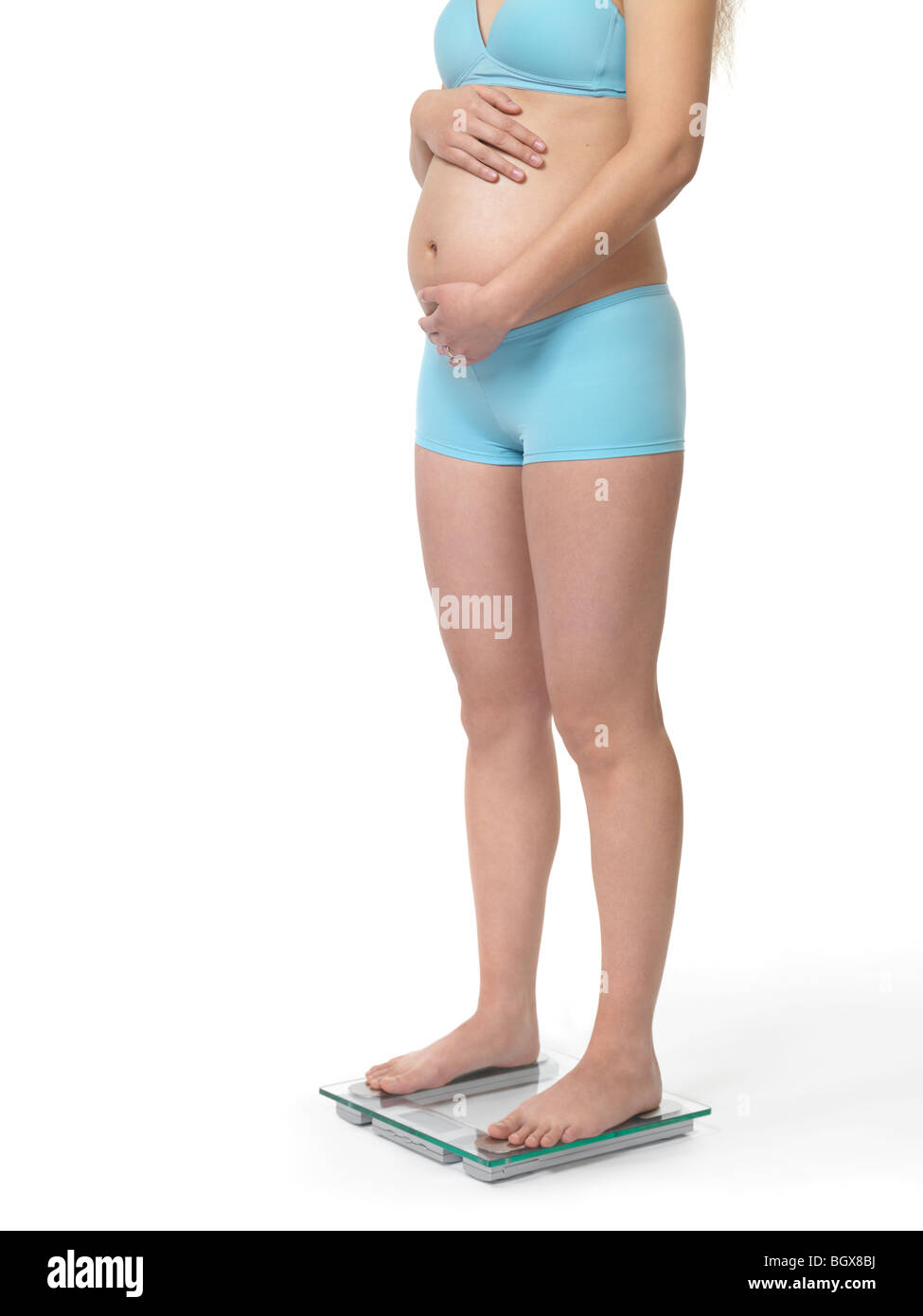 Schwangere Frau auf einer Waage stehen. Isoliert auf weißem Hintergrund. Stockfoto
