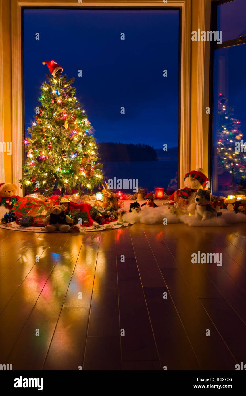 Weihnachtsbaum mit Lichtern, Dekorationen und Geschenke in einem Fenster in der Abenddämmerung, The Artists Point, Hyde Creek, Port McNeill, Nord-Va Stockfoto