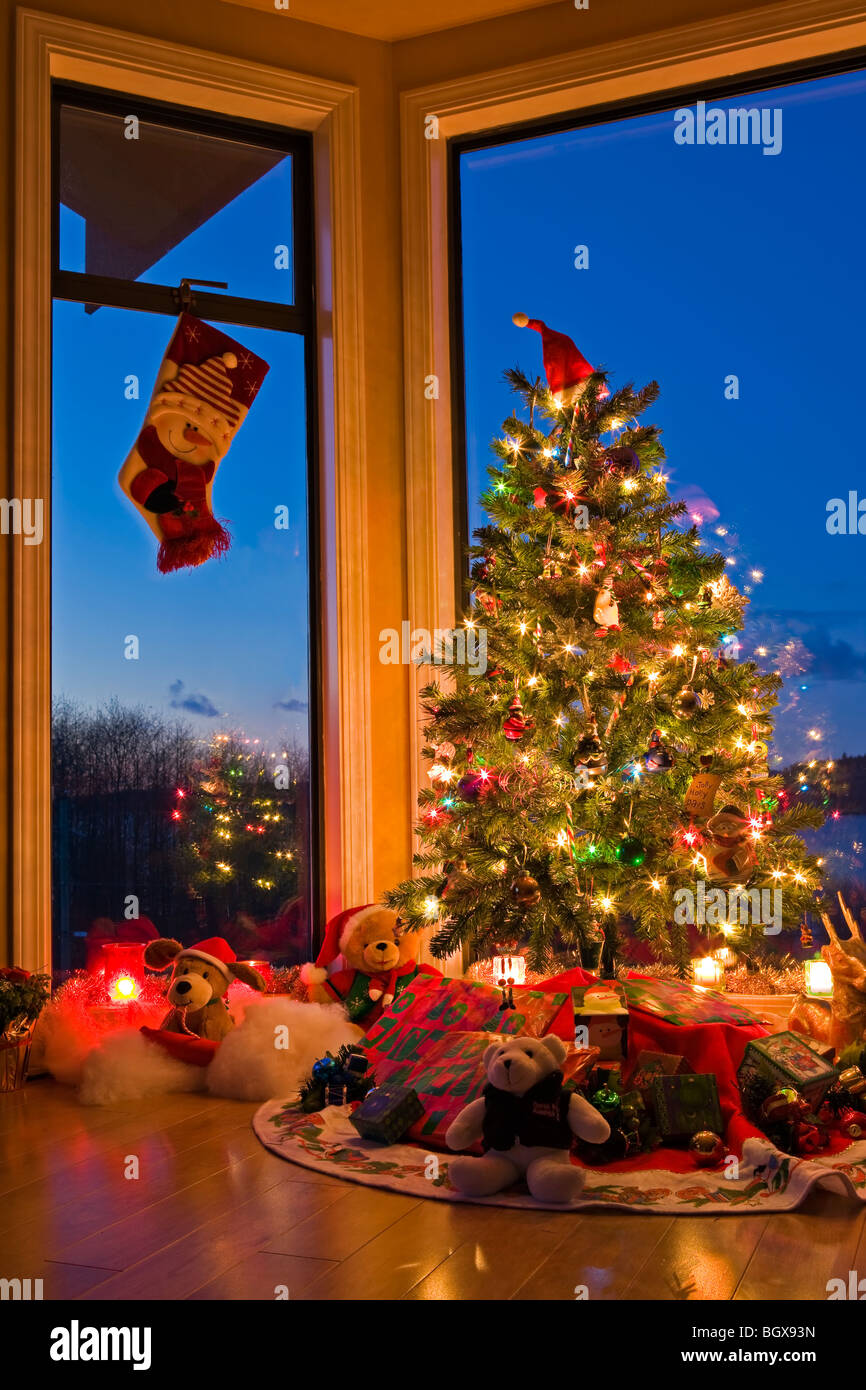 Weihnachtsbaum mit Lichtern, Dekorationen, Geschenke und ein Weihnachts-Strumpf Aufhängen in einem Fenster in der Abenddämmerung, The Artists Point Hyde Stockfoto