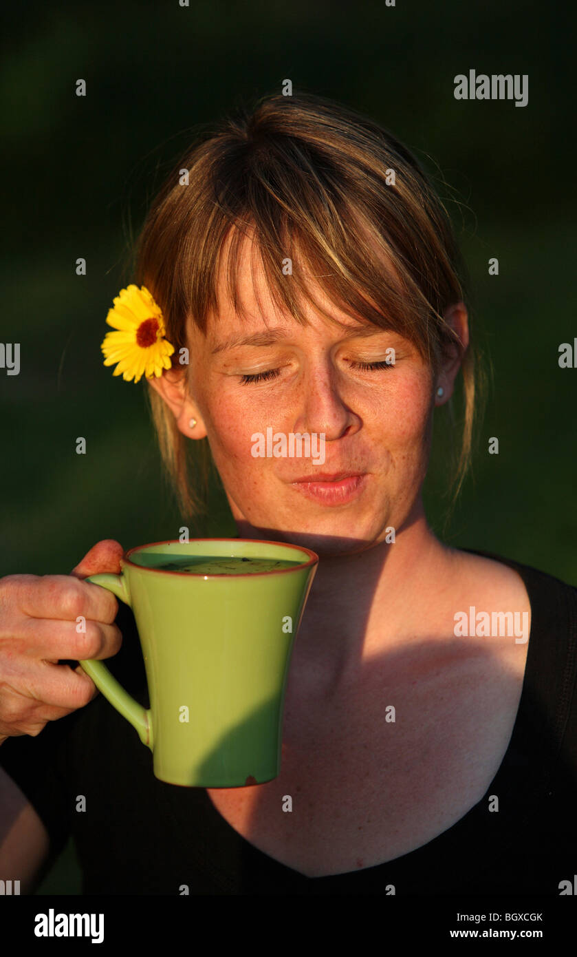 Frau mit einer Blume im Haar, mit einer Tasse Stockfoto