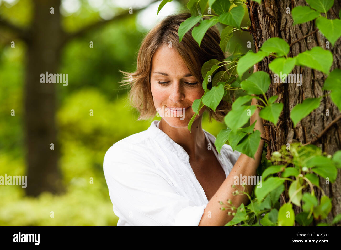 Frau neben einem Baum lächelnd Stockfoto