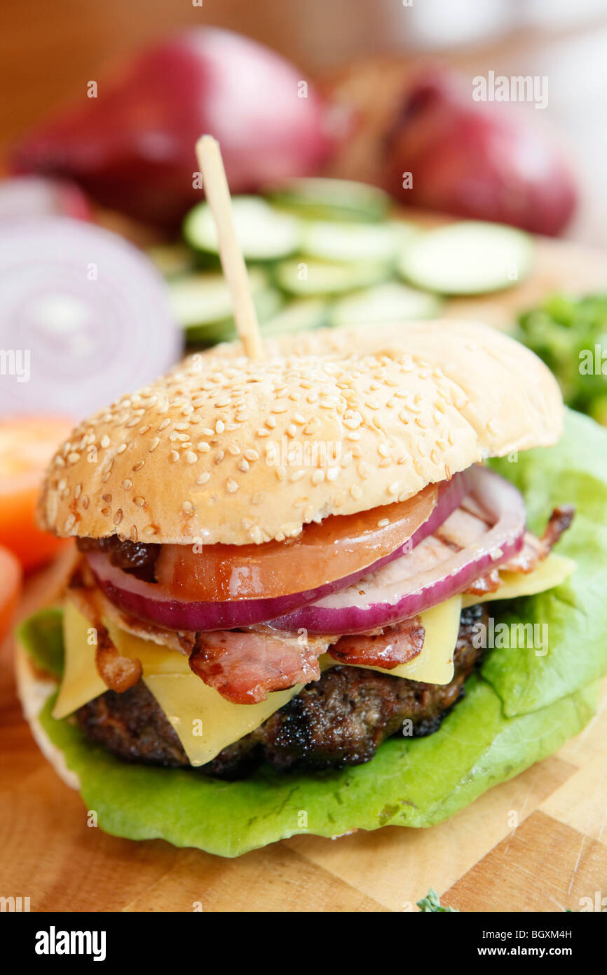 Burger mit Käse, Speck und Beilagen in einem Restaurant zubereitet wird Stockfoto