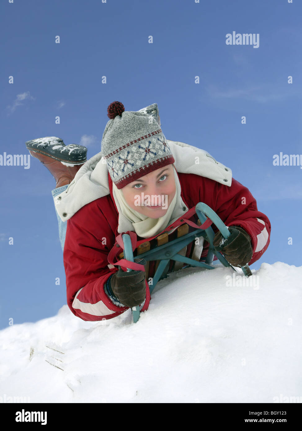 Junge Frau lächelnd hinunter den Hügel Bauchlandung im winter Stockfoto