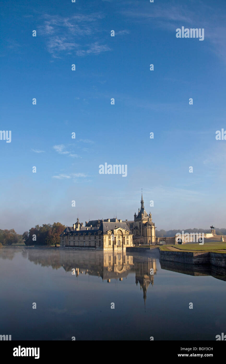 Château de Chantilly, Oise Frankreich. Wasser Reflexion atmosphärischen Sonnenlicht, blauen Morgenhimmel. Vertikale 100377 Chantilly Stockfoto