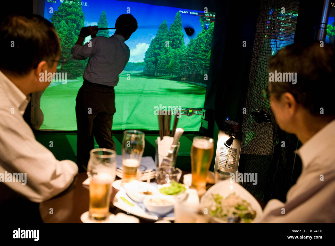 Japanischen Gehaltsempfänger Kunden trinken Bier und EDV Golf spielen, in der Golfbar, Tokio, Japan. Stockfoto