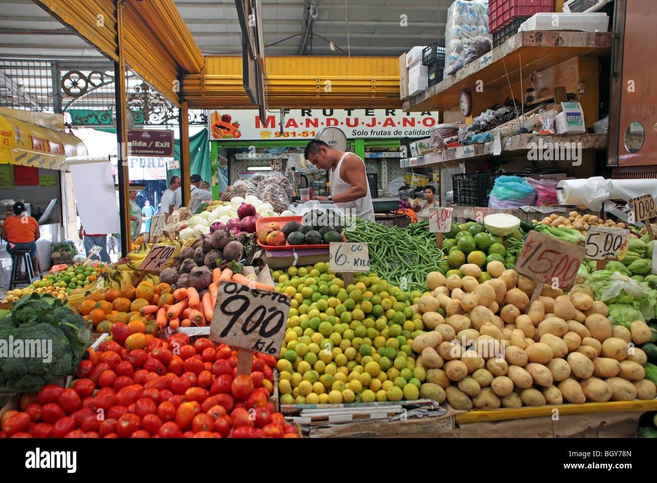 Gemüse und Obst stehen in einem mexikanischen floh- und Lebensmittel-Markt, Mazatlan Mexiko. Besitzer in Kurzarm Hemd hinter Theke. Stockfoto