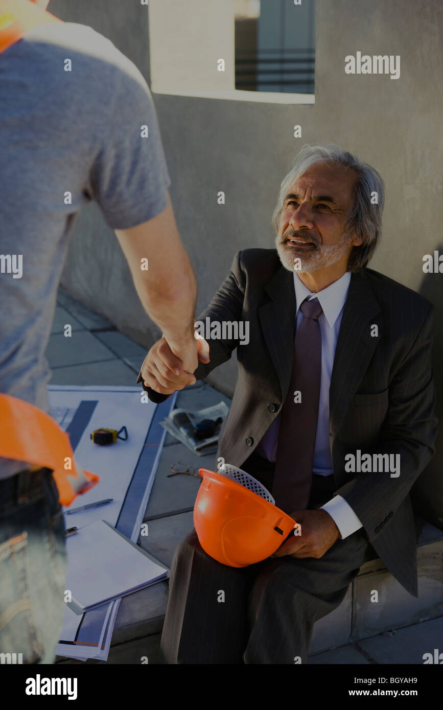 Architekt Händeschütteln mit Bauarbeiter auf der Baustelle zugeschnitten Stockfoto