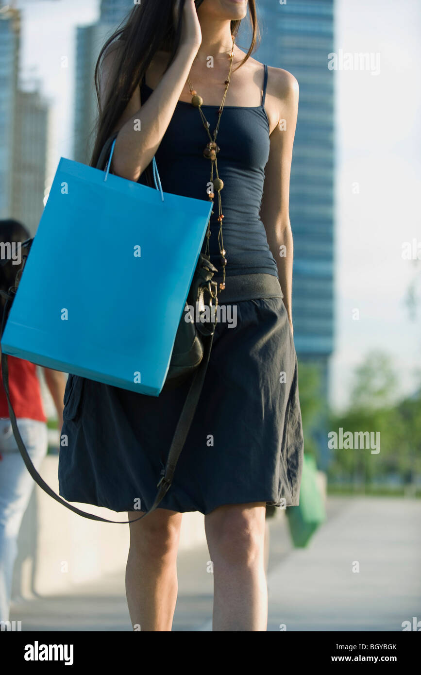 Frau mit Einkaufstasche zu Fuß auf dem Bürgersteig, beschnitten Stockfoto
