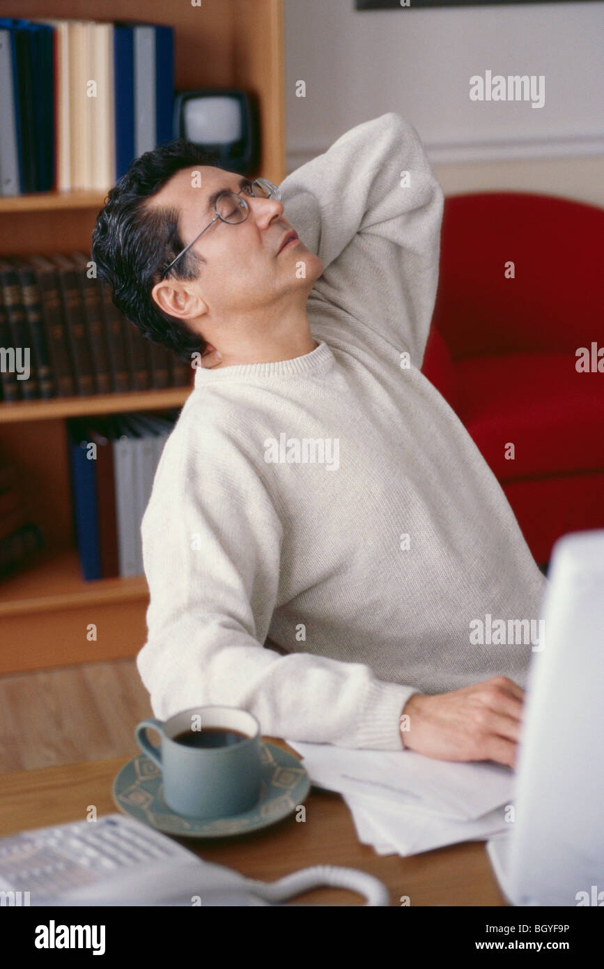Mann stretching am Schreibtisch Stockfoto