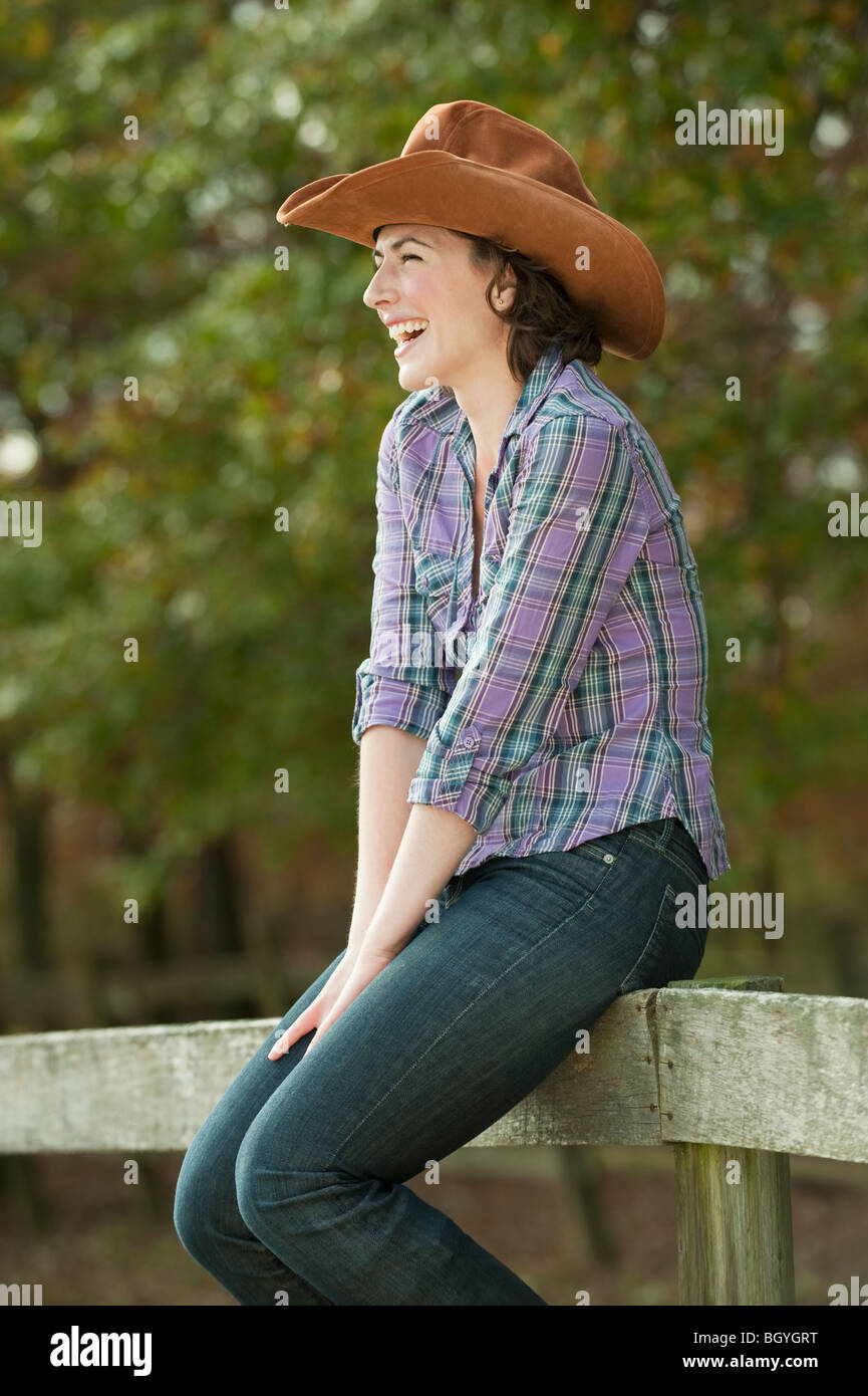 Frau sitzt auf Zaun Stockfoto