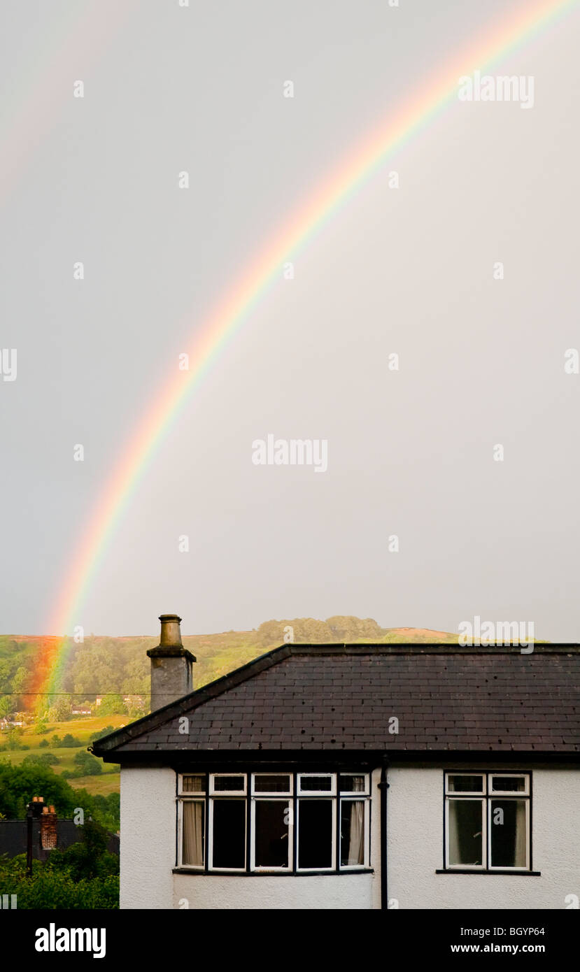 Regenbogen über Vorstadthaus mit Hügeln in der Ferne gewölbt Stockfoto