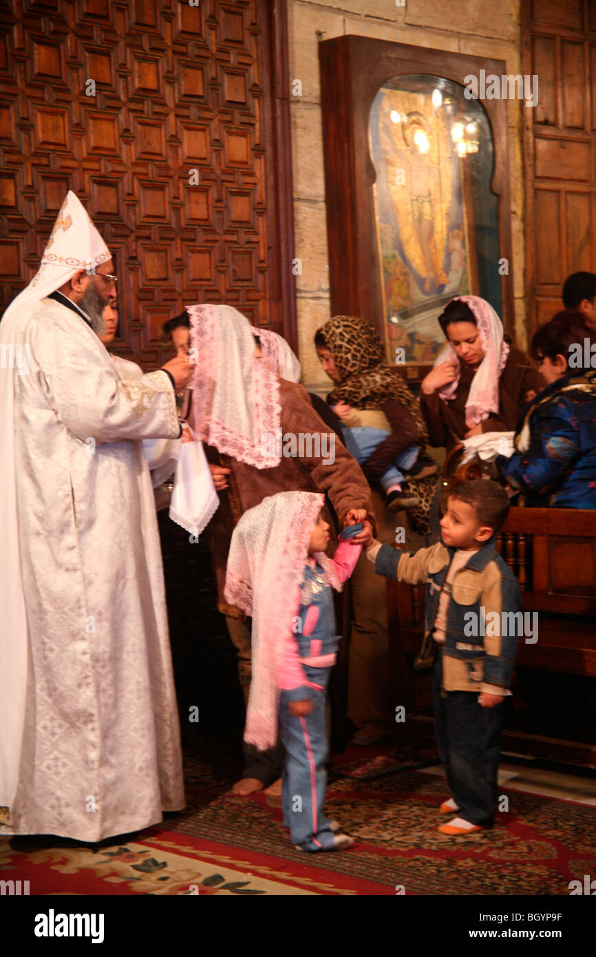 Frau küsst die Hand des Priesters nach der koptischen christlichen Kommunion in der Deir al-Adra Kirche in Maadi, Kairo, Ägypten Stockfoto